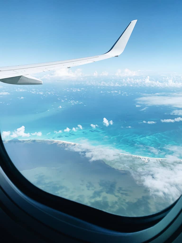View of the blue and green ocean out the window of a plane in flight. #solofemaletravel #travel