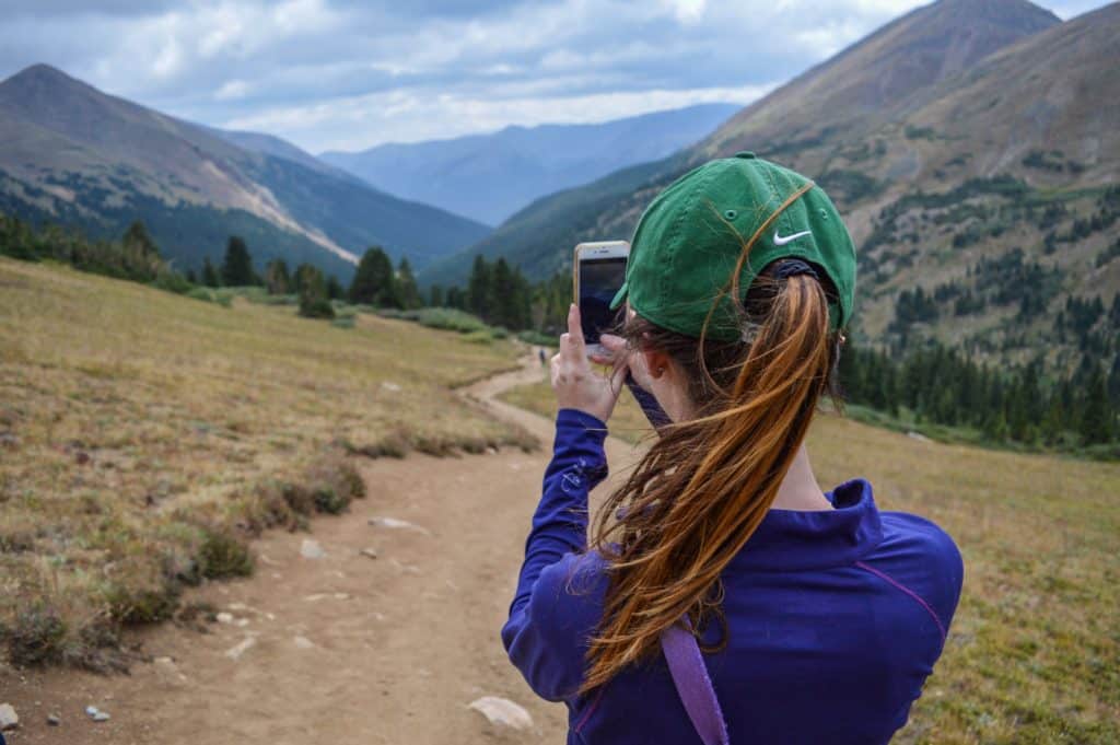 How To Travel By Yourself. Girl taking photo of mountains alone. 