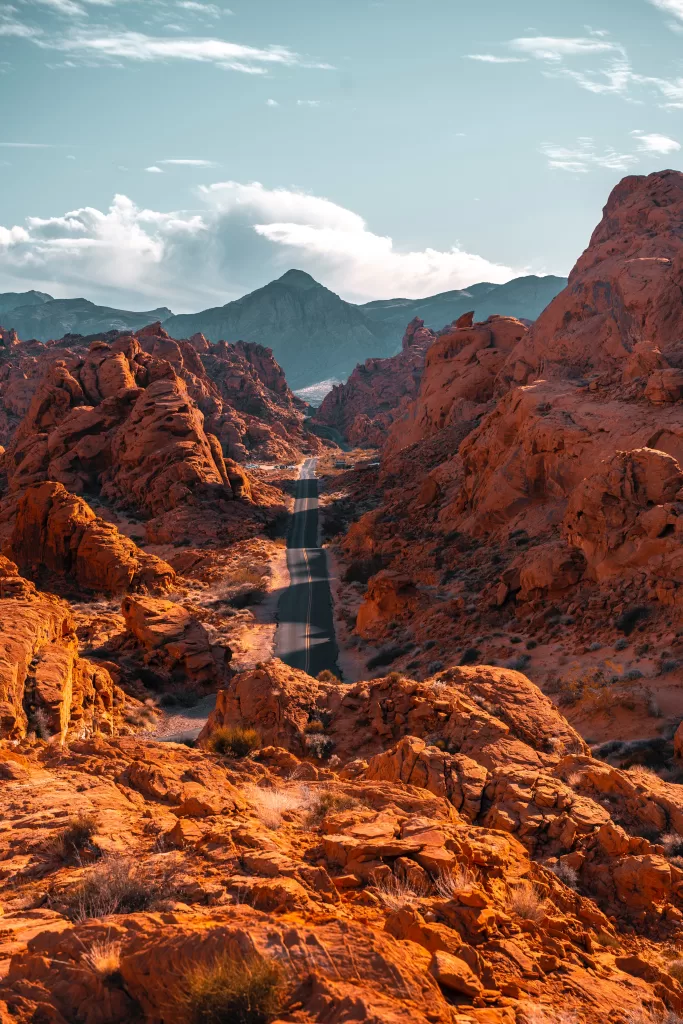 Red rocks and mountains with winding road in between. #toptenroadtripessentials #roadtrip #roadtripessentials #roadtripaesthetic #roadtripoutfit